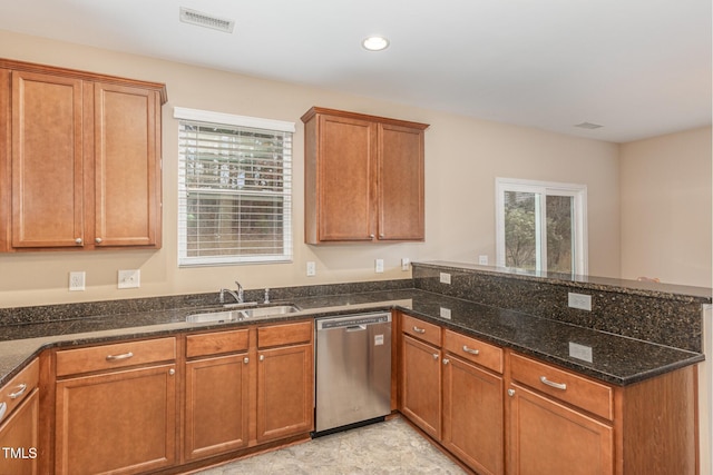 kitchen with a sink, visible vents, stainless steel dishwasher, brown cabinets, and dark stone counters