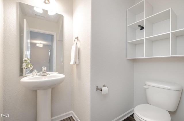 half bath featuring visible vents, toilet, and baseboards