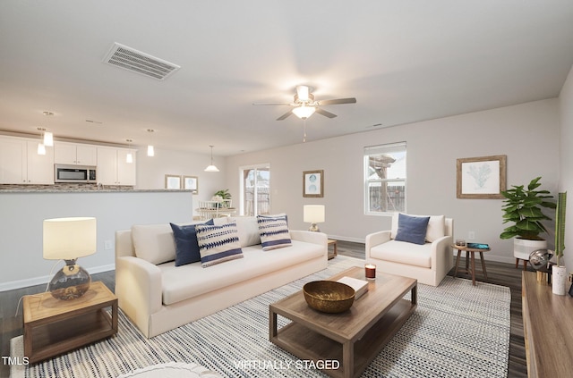 living room with a wealth of natural light, wood finished floors, visible vents, and baseboards