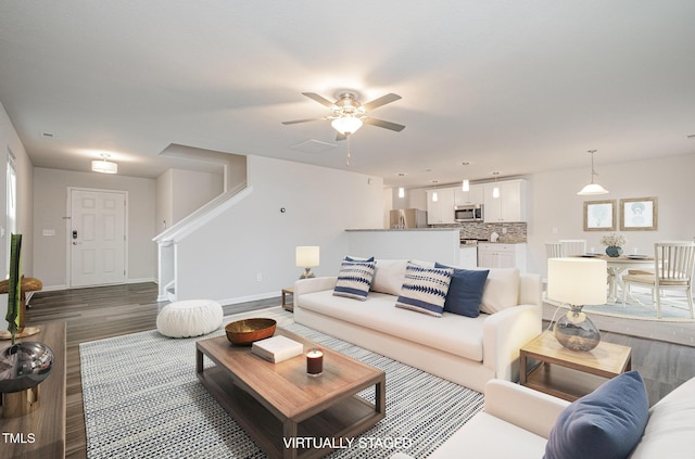 living area with ceiling fan, stairway, baseboards, and wood finished floors