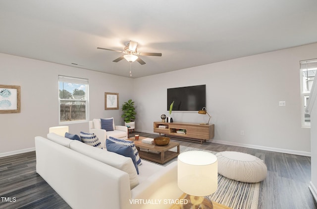 living area featuring dark wood-type flooring, a ceiling fan, and baseboards