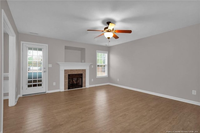 unfurnished living room featuring a fireplace, wood-type flooring, and ceiling fan