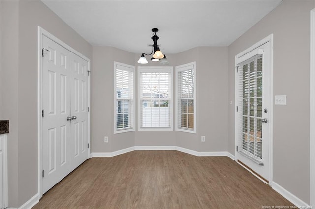 unfurnished dining area featuring hardwood / wood-style floors and an inviting chandelier