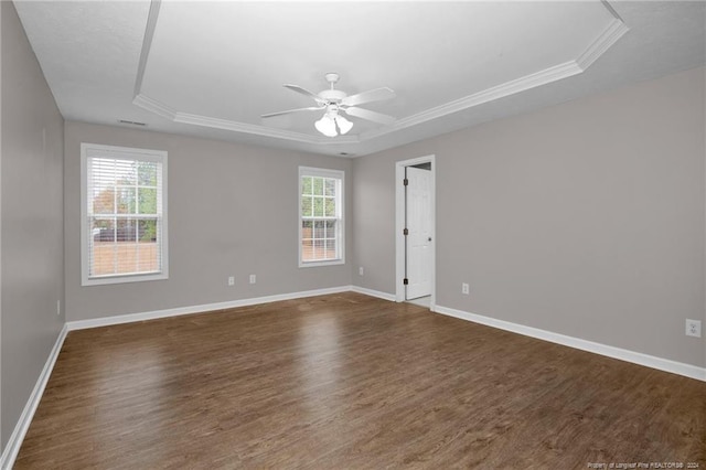 unfurnished room featuring a raised ceiling, ceiling fan, crown molding, and dark wood-type flooring