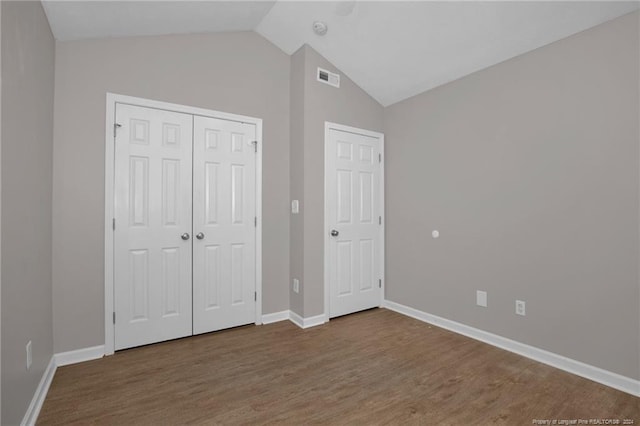 unfurnished bedroom with hardwood / wood-style flooring, vaulted ceiling, and a closet