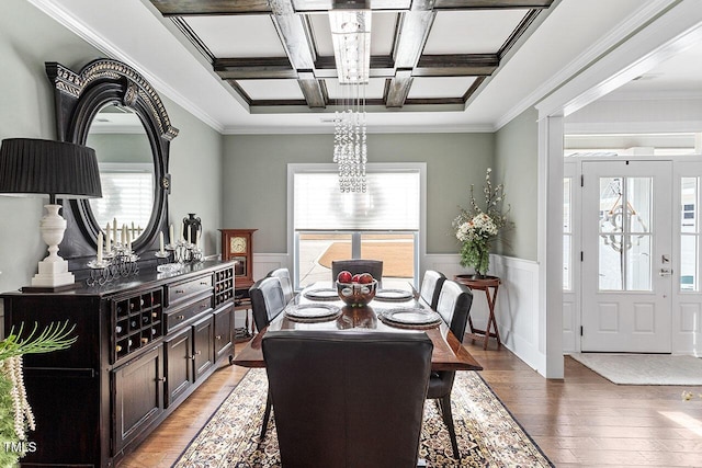 dining room with hardwood / wood-style floors, coffered ceiling, crown molding, a notable chandelier, and beam ceiling