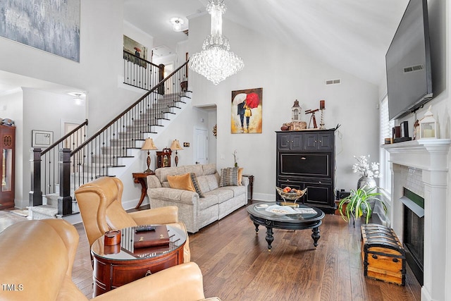 living room with a chandelier, high vaulted ceiling, wood-type flooring, and a brick fireplace