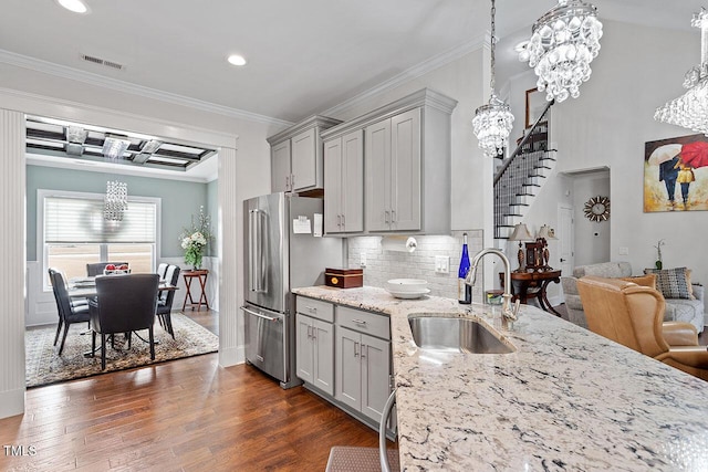 kitchen featuring crown molding, decorative light fixtures, sink, a notable chandelier, and stainless steel refrigerator