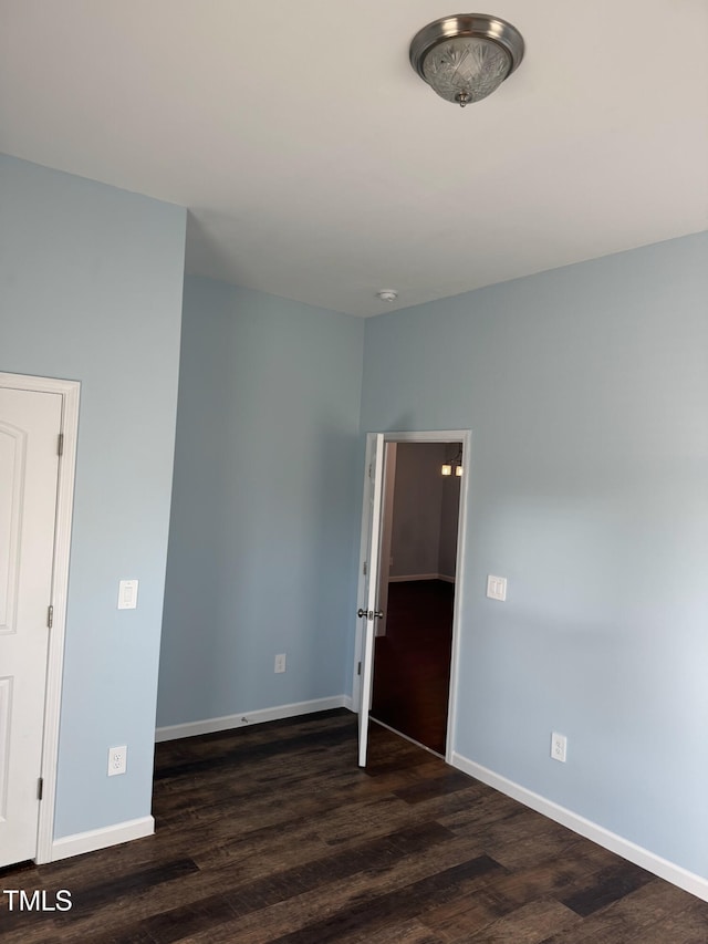 unfurnished room with dark wood-type flooring and baseboards