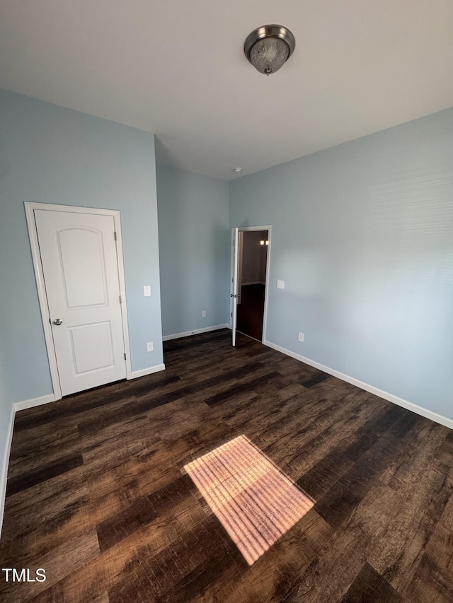 unfurnished bedroom with dark wood-style floors and baseboards