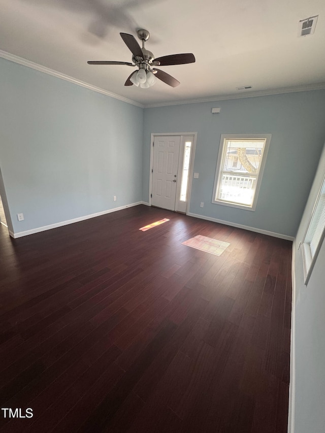 spare room with ceiling fan, visible vents, baseboards, dark wood-style floors, and crown molding