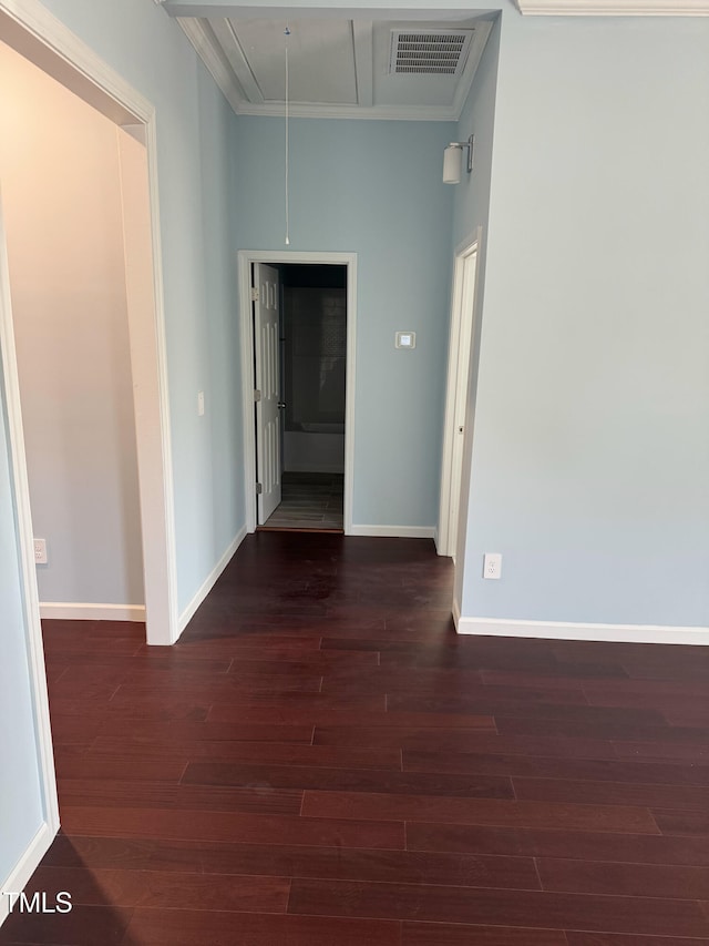 spare room with attic access, baseboards, visible vents, dark wood finished floors, and crown molding