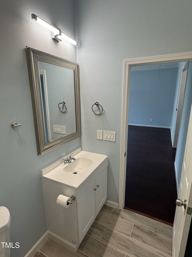 bathroom featuring wood tiled floor, toilet, vanity, and baseboards