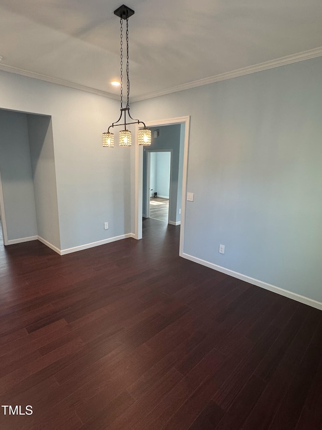 spare room with crown molding, dark wood finished floors, and baseboards