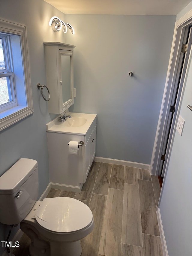 bathroom featuring vanity, toilet, and baseboards