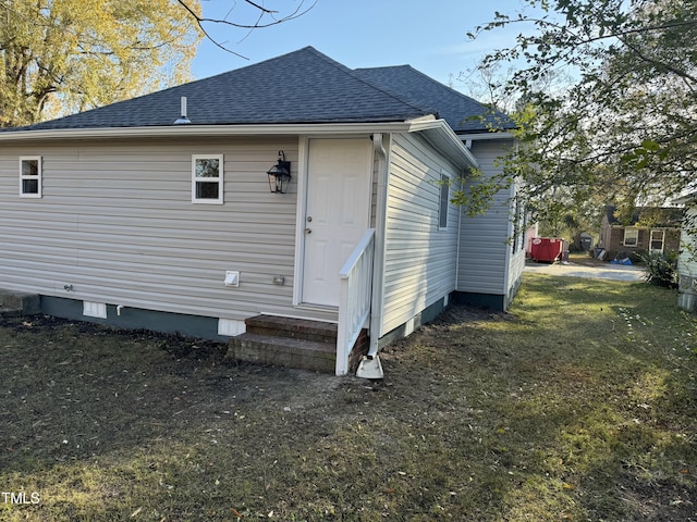 rear view of house featuring entry steps, roof with shingles, crawl space, and a lawn