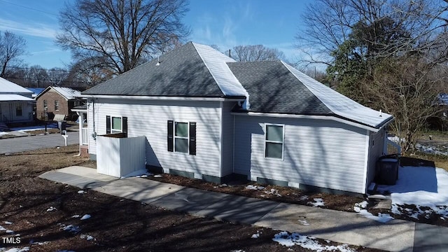 snow covered property featuring roof with shingles