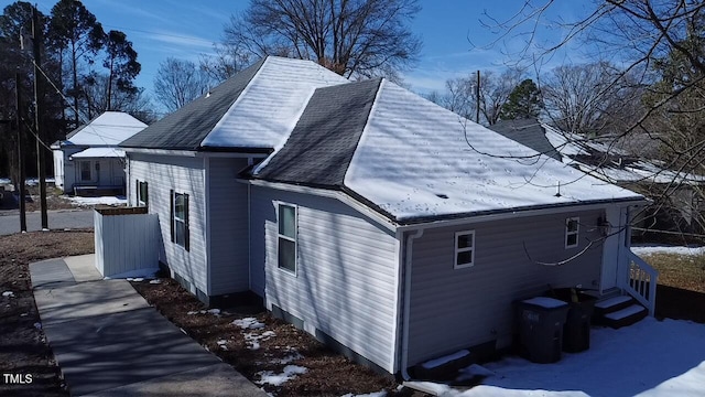 view of snowy exterior with roof with shingles