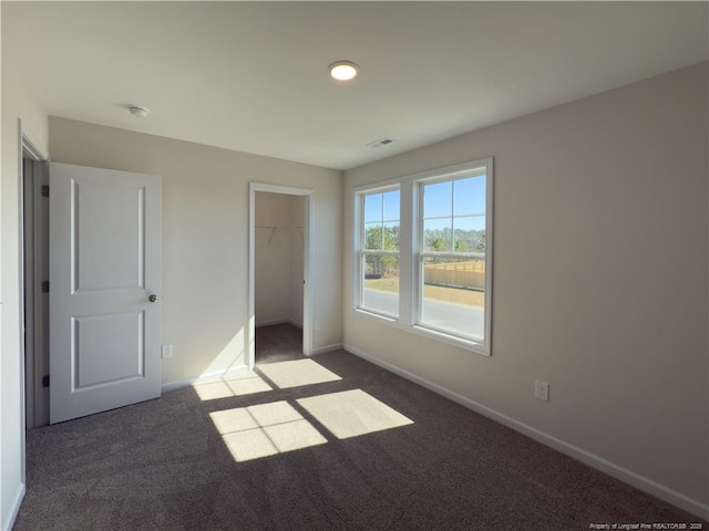 unfurnished bedroom featuring baseboards, visible vents, and dark colored carpet