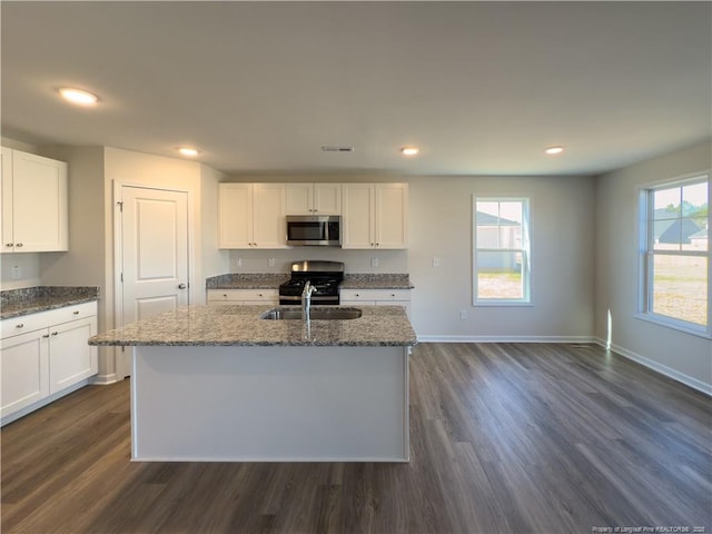 kitchen featuring white cabinets, stainless steel appliances, a sink, and an island with sink