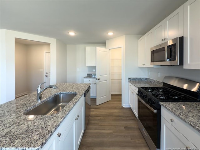 kitchen with stainless steel appliances, white cabinets, a sink, and light stone counters