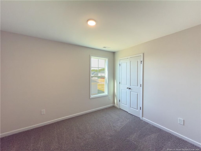 empty room featuring dark carpet and baseboards