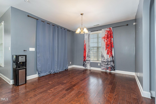 empty room featuring dark hardwood / wood-style floors and an inviting chandelier