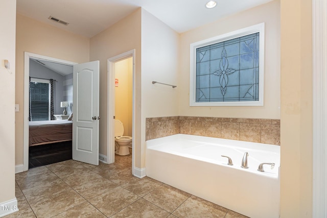 bathroom featuring tile patterned floors, a tub to relax in, and toilet