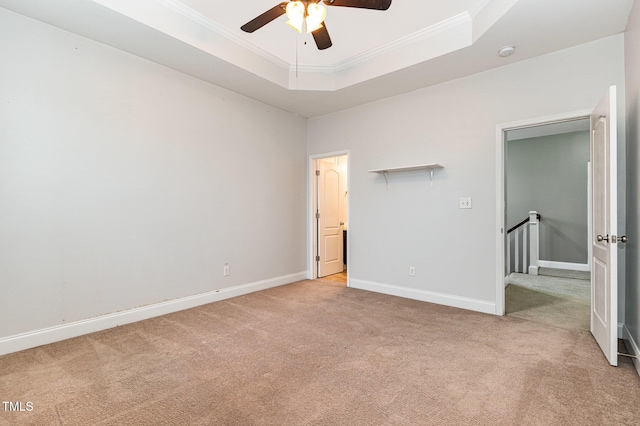 unfurnished bedroom featuring a raised ceiling, ceiling fan, light colored carpet, and ornamental molding