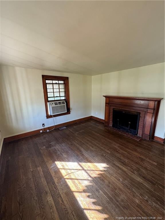 unfurnished living room with cooling unit, dark hardwood / wood-style floors, and a brick fireplace