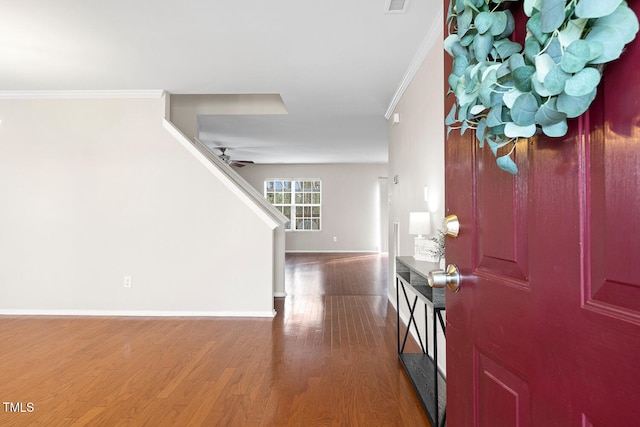 foyer featuring crown molding, a ceiling fan, wood finished floors, baseboards, and stairs