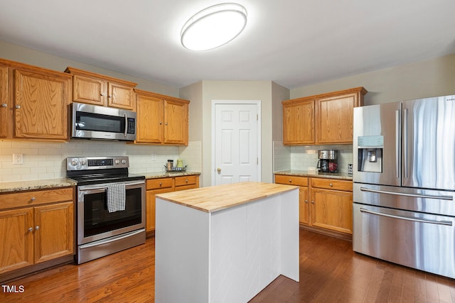 kitchen with appliances with stainless steel finishes, dark wood-style flooring, butcher block counters, and decorative backsplash