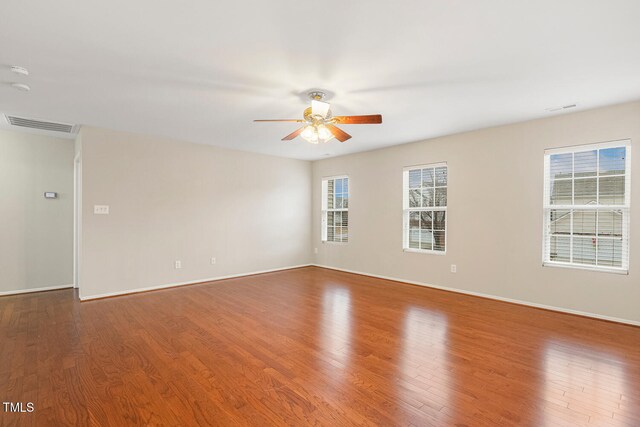 spare room featuring a wealth of natural light, visible vents, and wood finished floors