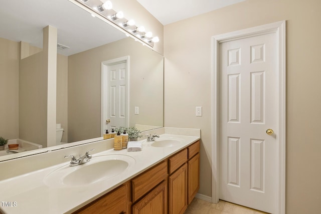 bathroom featuring double vanity, a sink, and toilet