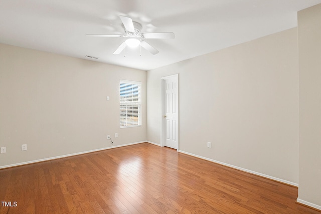 spare room with visible vents, wood finished floors, a ceiling fan, and baseboards