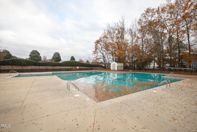 community pool featuring a shed, fence, a patio, and an outdoor structure