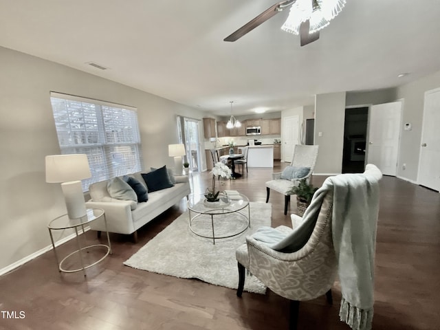 living room featuring a ceiling fan, visible vents, baseboards, and dark wood-style floors