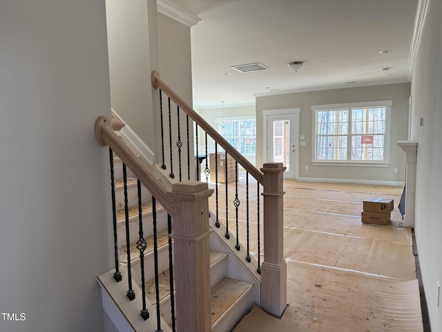 stairs featuring crown molding and plenty of natural light