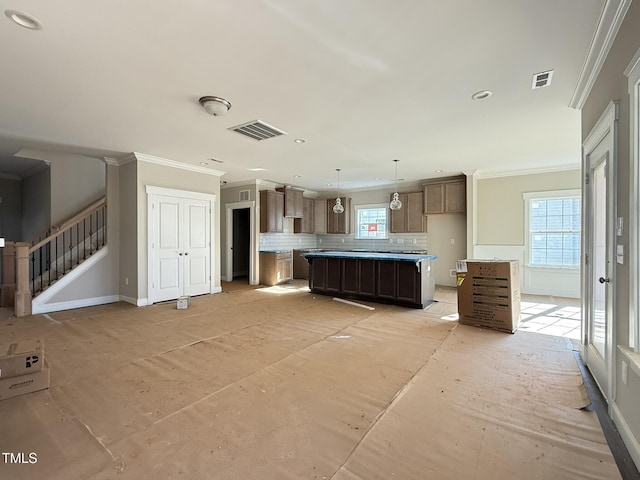 kitchen featuring tasteful backsplash, decorative light fixtures, a center island, ornamental molding, and plenty of natural light