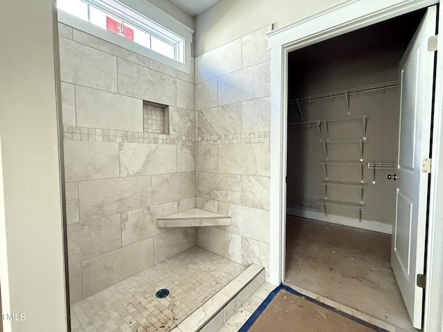 bathroom with a tile shower and concrete floors