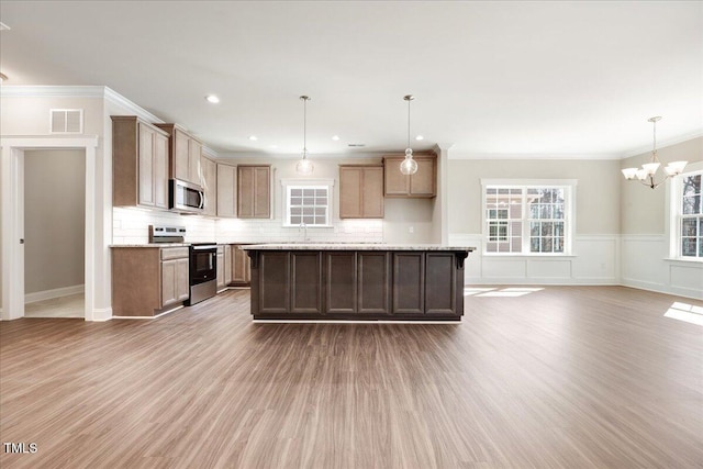 1975 Meadowview Dr, Graham, NC 27253 - kitchen featuring a wainscoted wall, visible vents, wood finished floors, appliances with stainless steel finishes, and a notable chandelier