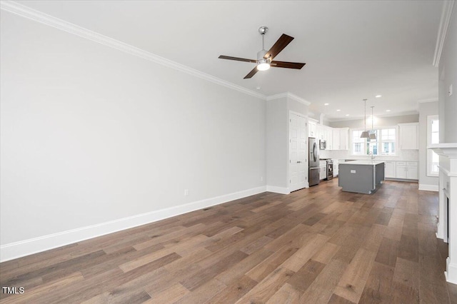 unfurnished living room featuring hardwood / wood-style flooring, ceiling fan, sink, and crown molding