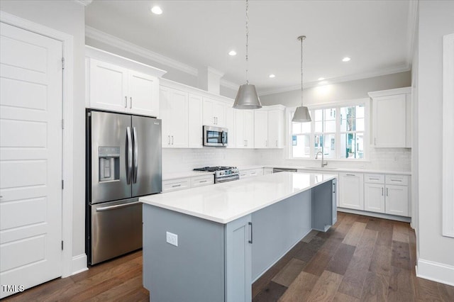 kitchen featuring hanging light fixtures, dark hardwood / wood-style floors, appliances with stainless steel finishes, a kitchen island, and white cabinetry