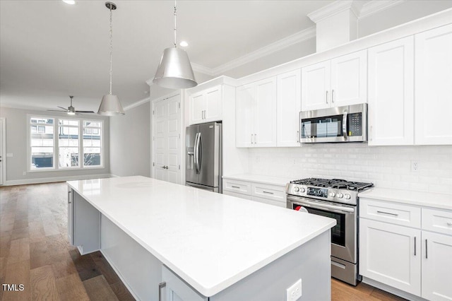 kitchen with stainless steel appliances, ceiling fan, decorative light fixtures, white cabinets, and a kitchen island