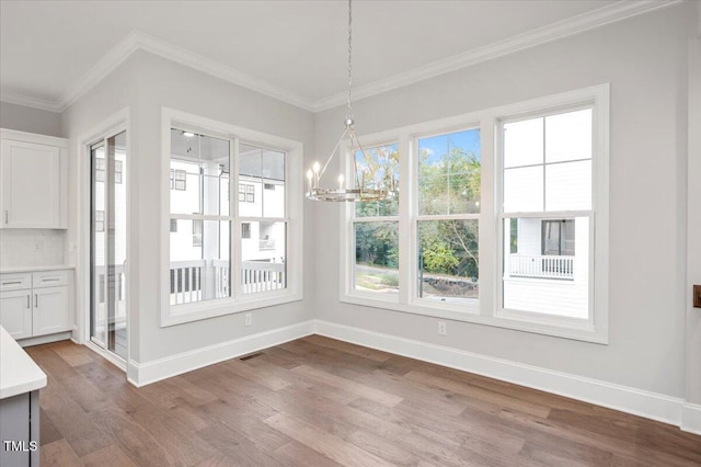 unfurnished dining area with light hardwood / wood-style floors, ornamental molding, and a chandelier