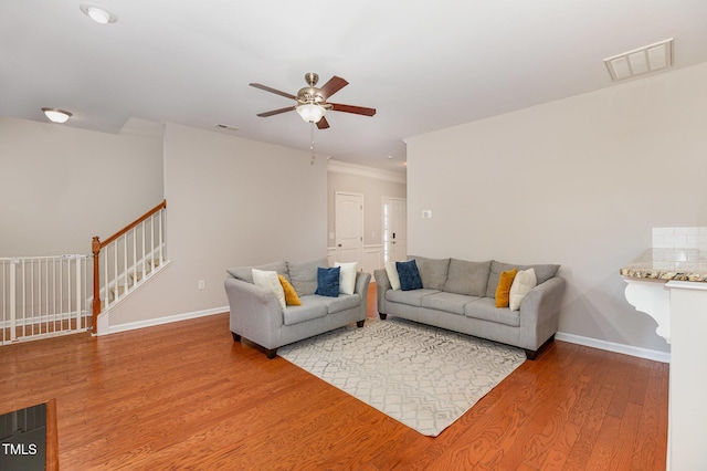 living room with hardwood / wood-style flooring, ceiling fan, and ornamental molding