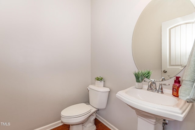 bathroom with wood-type flooring, toilet, and sink