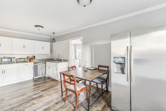 kitchen with pendant lighting, white cabinets, crown molding, appliances with stainless steel finishes, and dark hardwood / wood-style flooring