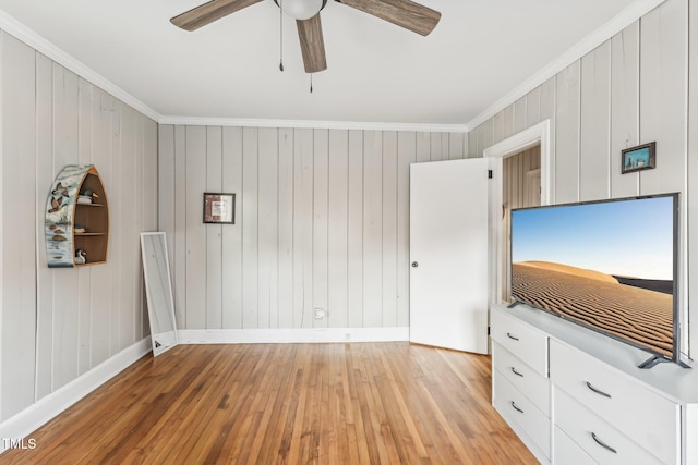 unfurnished bedroom featuring ceiling fan, light hardwood / wood-style flooring, wooden walls, and ornamental molding