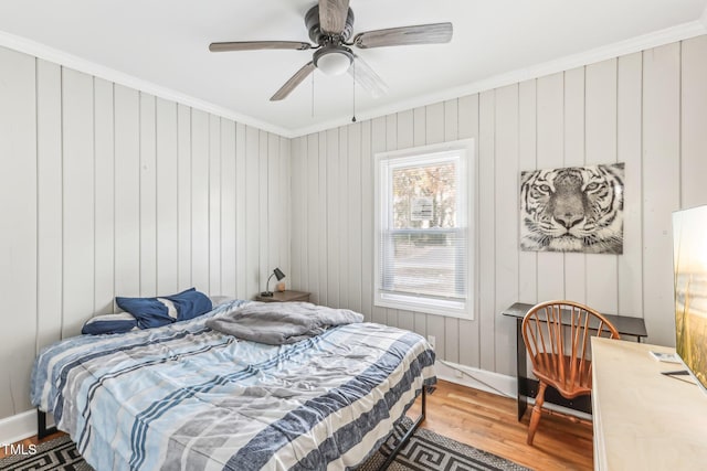 bedroom with hardwood / wood-style floors, ceiling fan, crown molding, and wooden walls